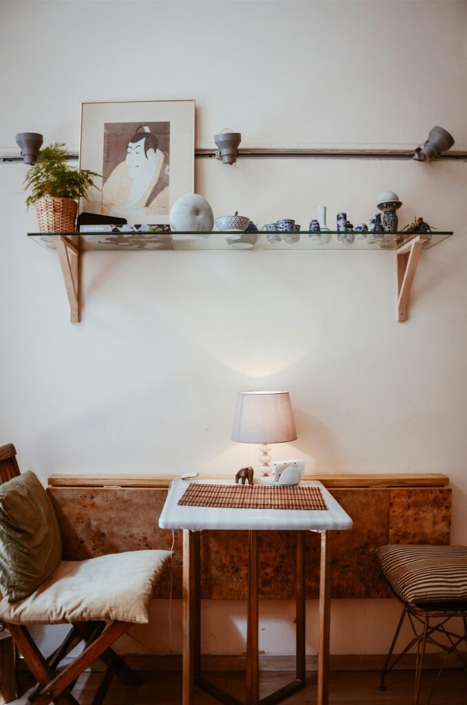 A cozy and modern living room featuring a decorative shelf, chairs, and a lamp on a wooden table.